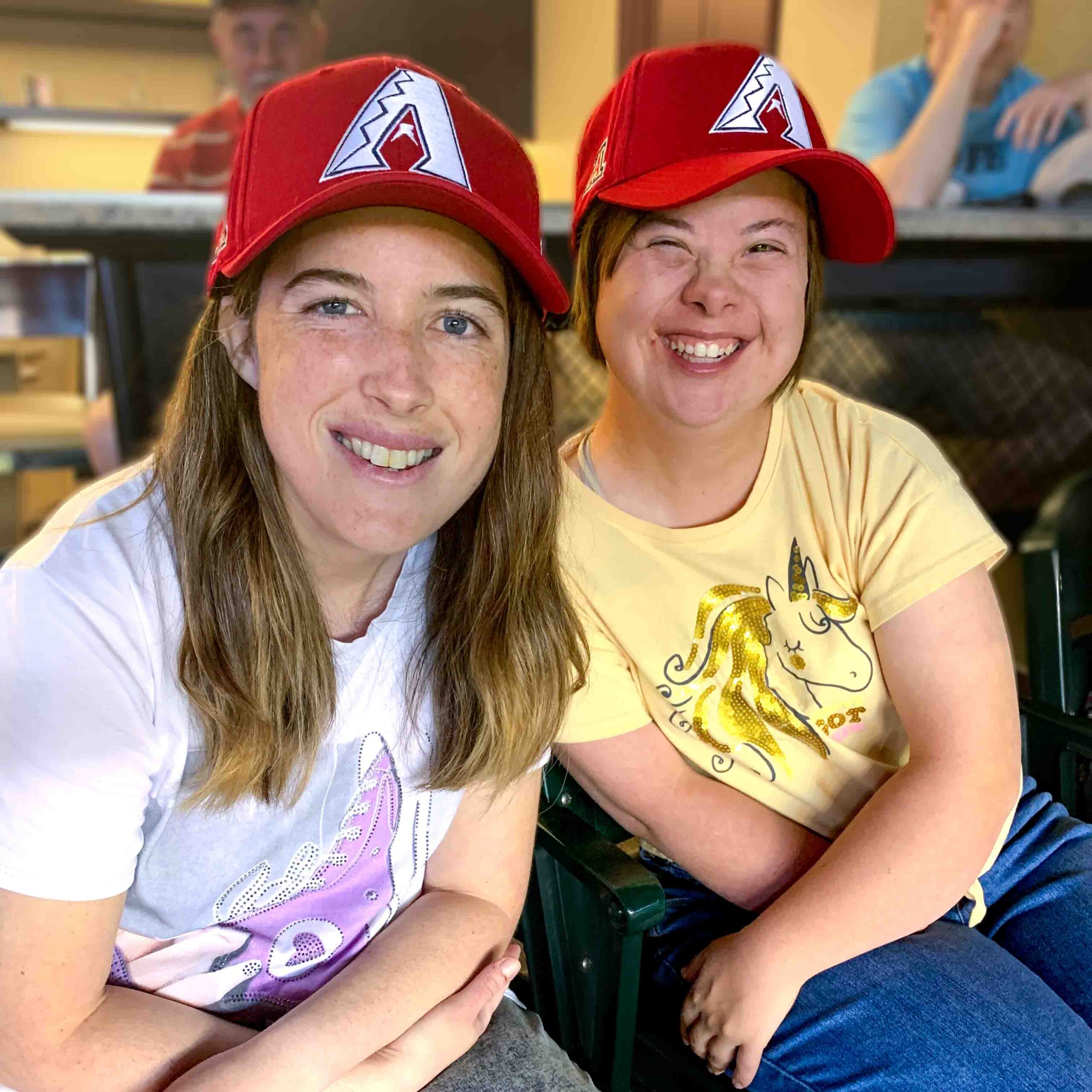 Female residents of Rainbow Acres wearing Arizona Diamond Back hats at the AZ DBacks game